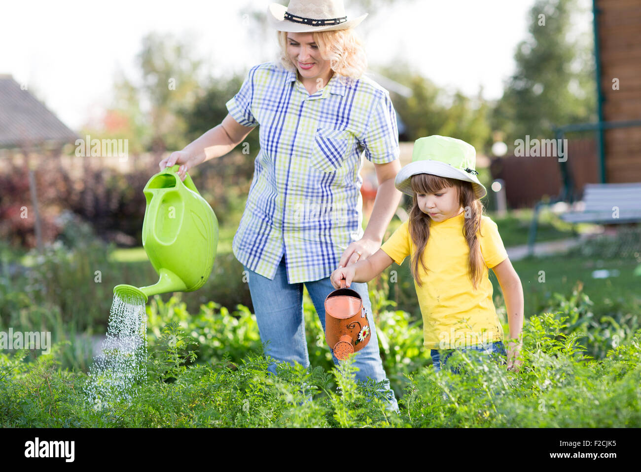 Mutter und Tochter, die Bewässerung von Pflanzen im Garten. Stockfoto