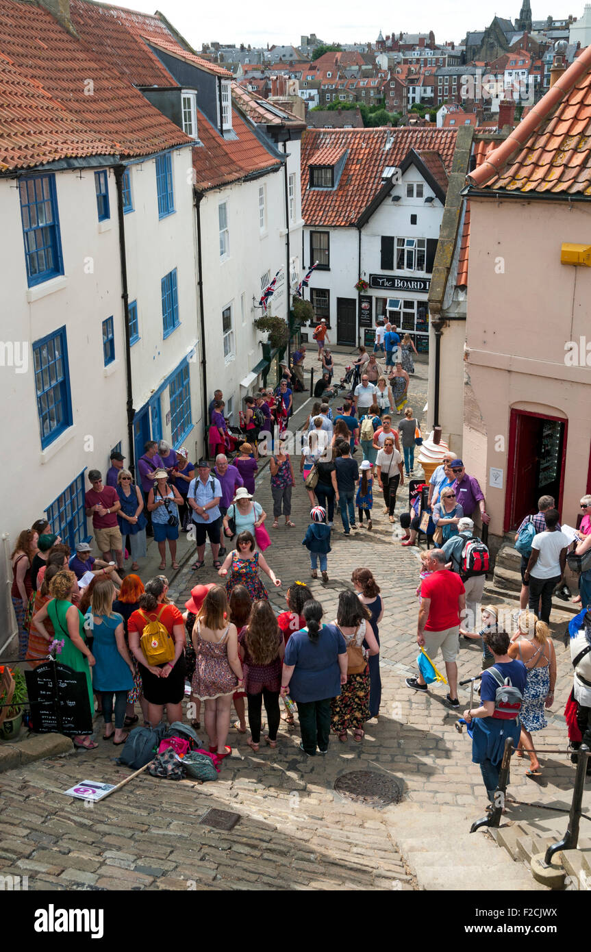 Church Lane, an der Basis der 199 Stufen, mit einem Chor singen im Vordergrund.  Whitby, Yorkshire, England, UK Stockfoto