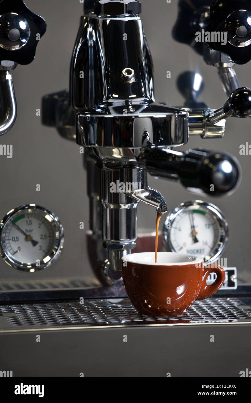 Edelstahl-Espresso-Maschine in Aktion mit braunen Espressotasse Stockfoto