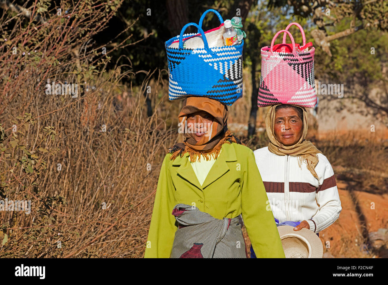 Zwei madagassischen Frauen mit Einkaufstasche auf ihren Kopf zu Fuß zum Wochenmarkt in Ambalavao, Haute Matsiatra, Madagaskar, Afrika Stockfoto