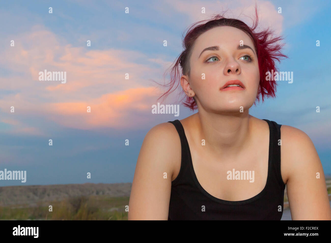 Eine attraktive junge Frau posiert mit nachdenklichen, ernst und albern Ausdrücke im Freien vor einem blauen Himmel. Stockfoto