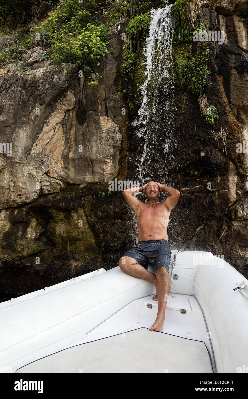 Man genießt einen erfrischenden Wasserfall vom Bug eines Bootes Dusche, Amalfiküste, Italien Stockfoto