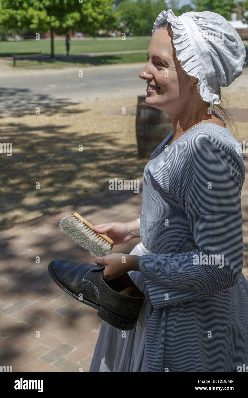 Periode Schauspieler verkleidet als Dienstmädchen lächelnd und hält einen Schuh Colonial Williamsburg lebendige Geschichte Museum Virginia gereinigt werden Stockfoto