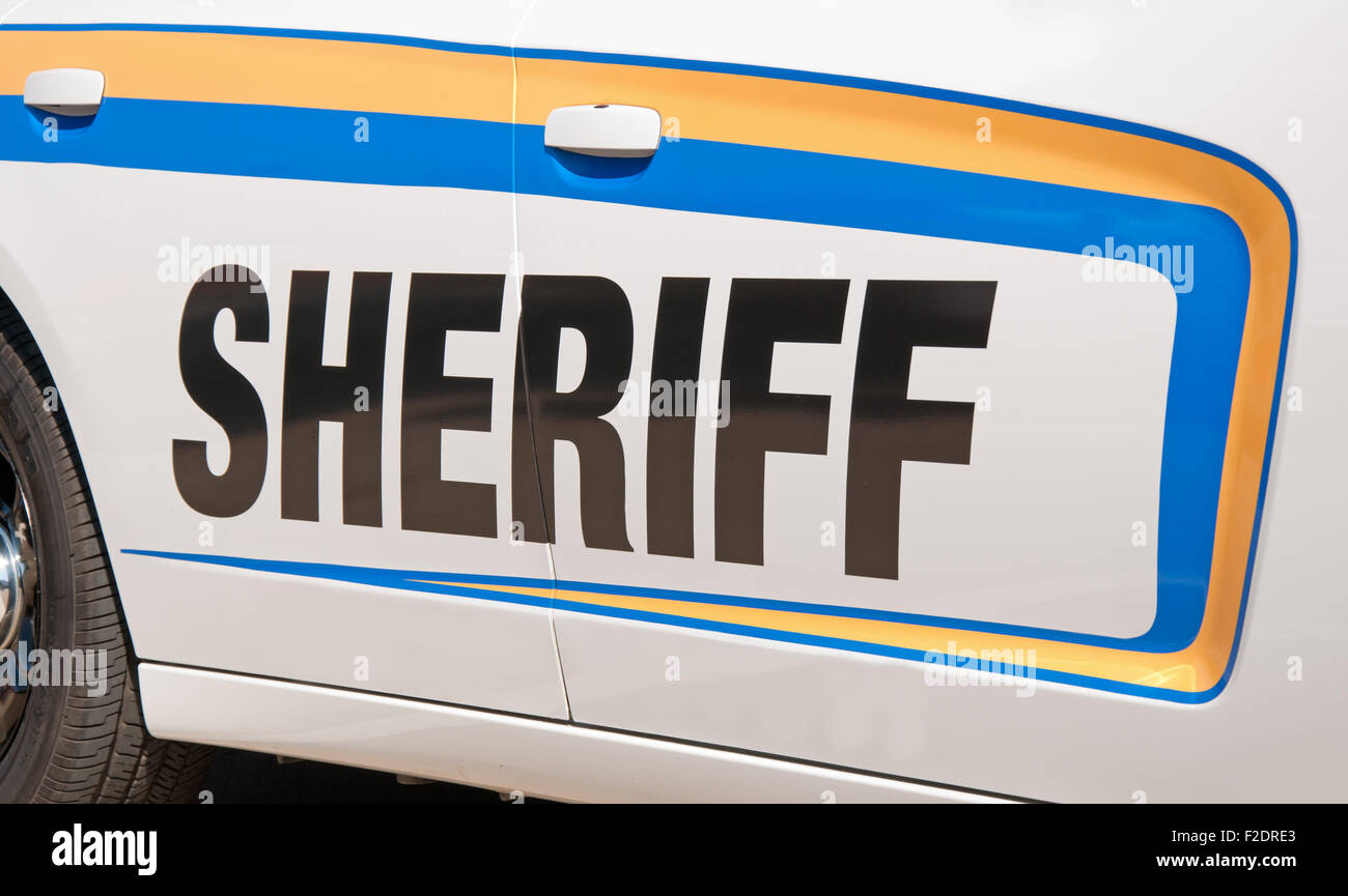 Sheriff Text in schwarz auf einem weißen Streifenwagen, gesäumt von gelben und blauen Aufkleber Streifen Stockfoto