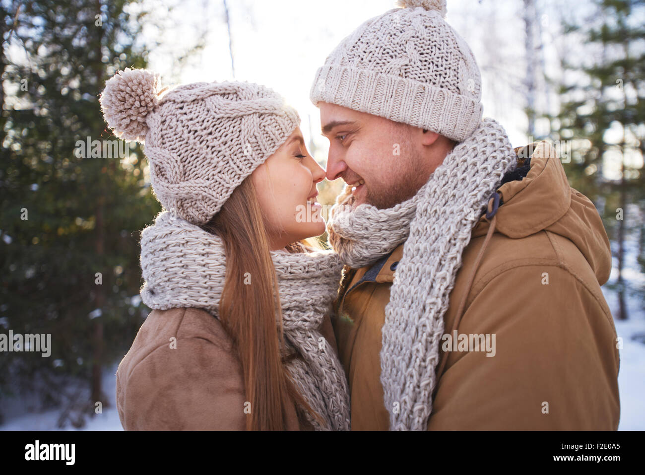 Glücklicher junger Mann und Frau in Winterwear flirten außerhalb Stockfoto