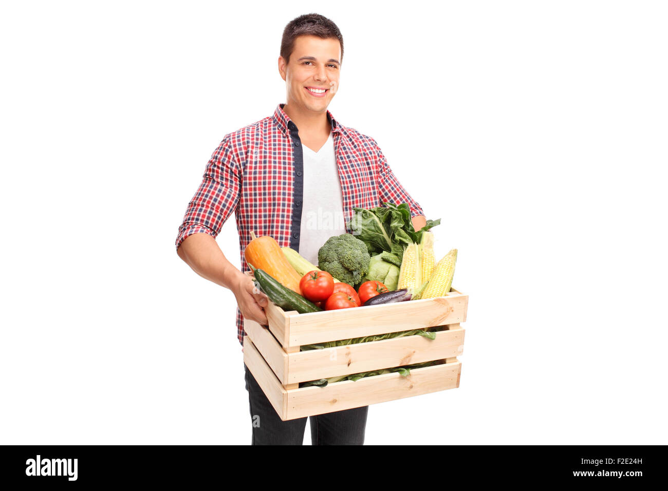 Junge fröhliche Mann trägt eine hölzerne Kiste voller frisches Gemüse isoliert auf weißem Hintergrund Stockfoto
