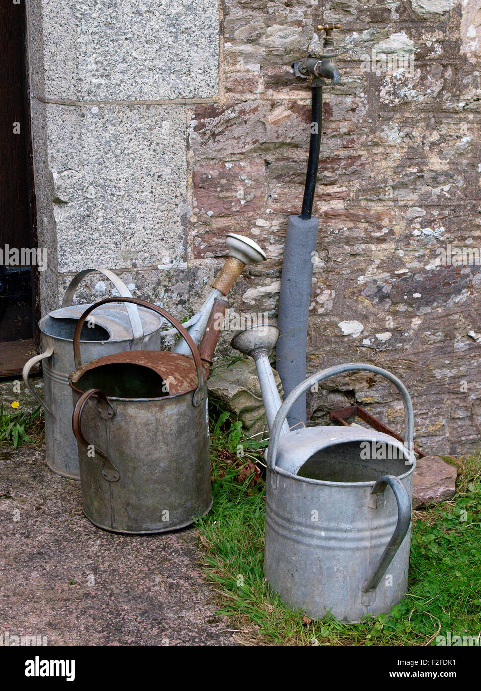 Drei Gießkannen durch Tippen auf einem Friedhof, Devon, UK Stockfoto