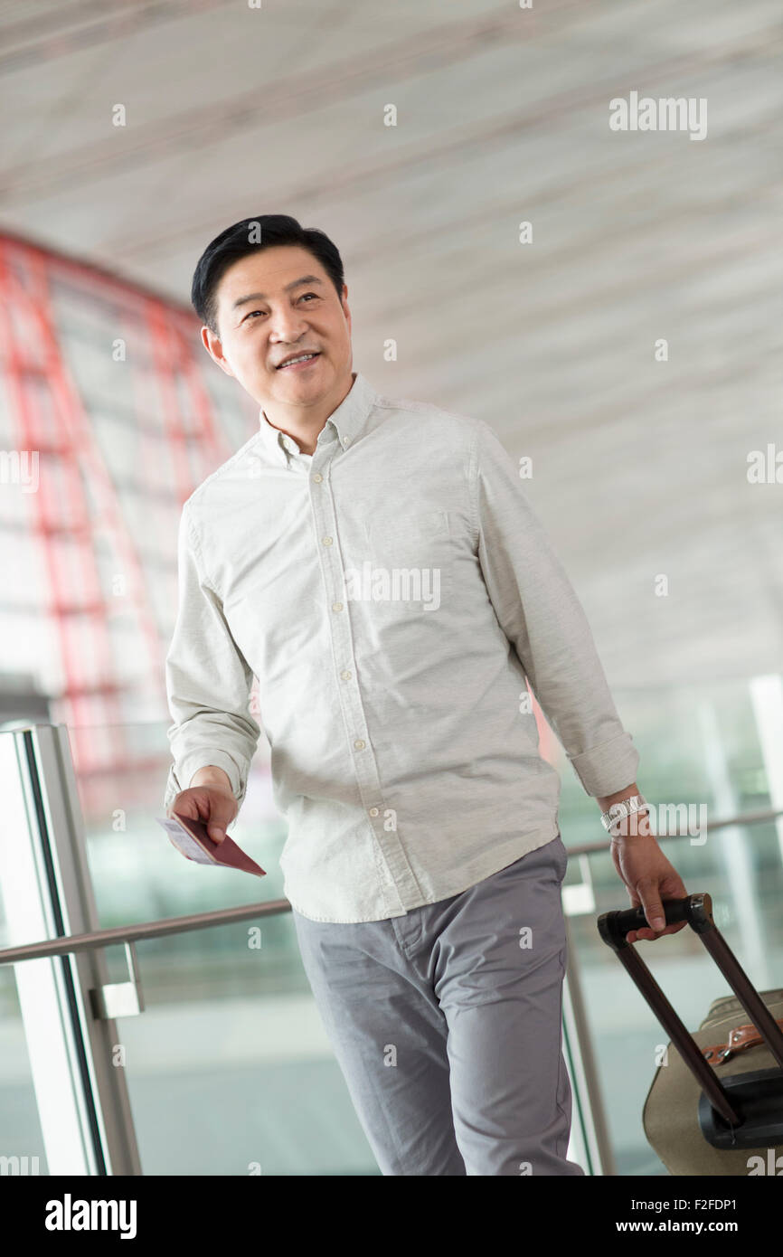 Reifer Mann zu Fuß in Flughafen mit Koffer Stockfoto