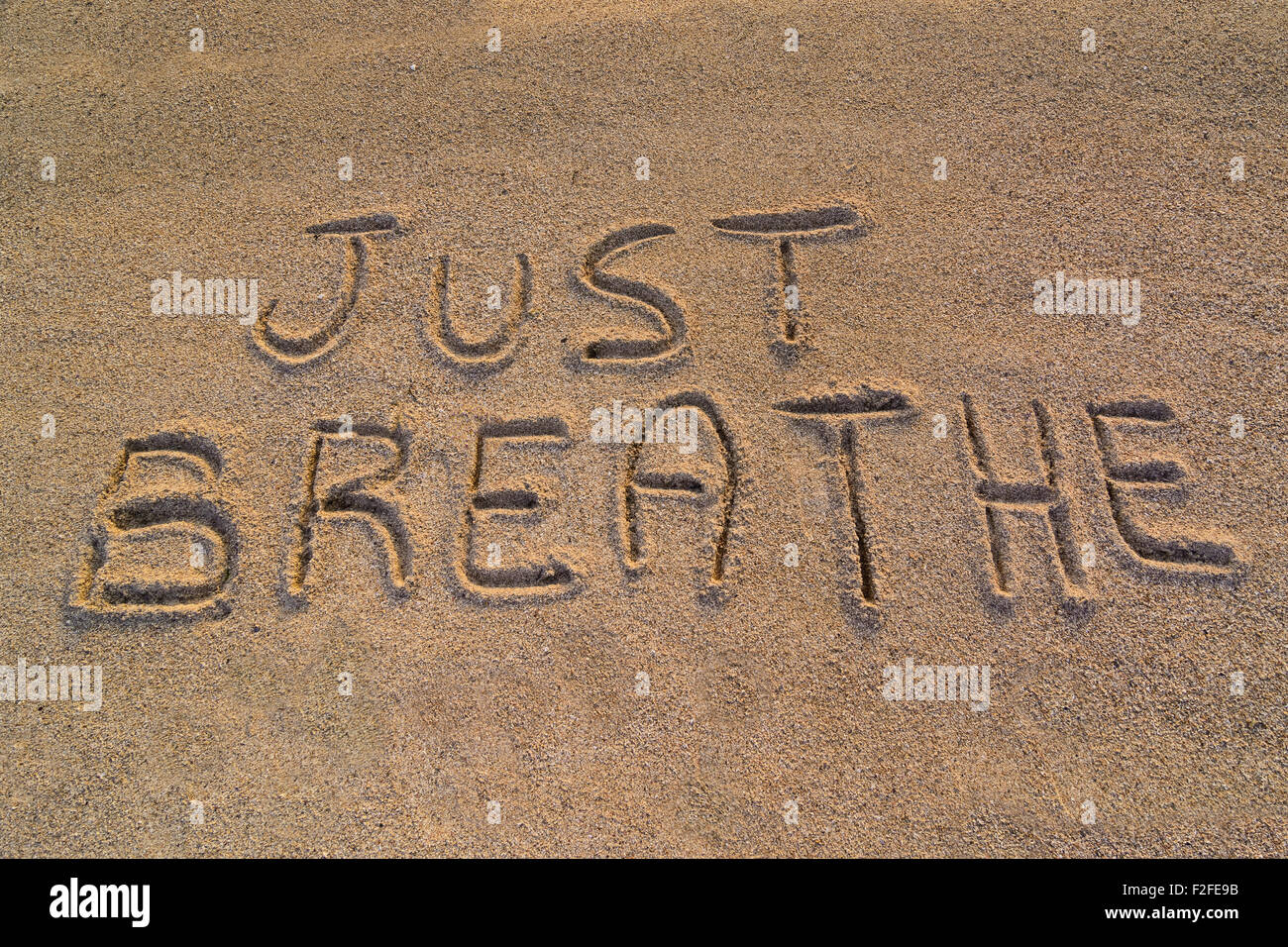 Im Bild die Worte auf dem Sand "einfach atmen". Stockfoto
