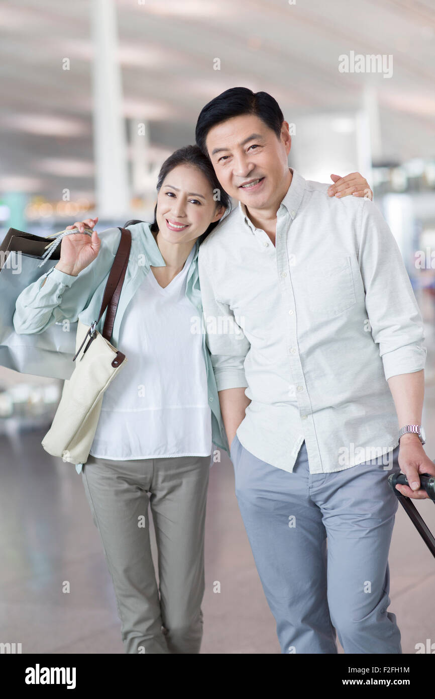 Älteres Paar warten am Flughafen mit Einkaufstüten Stockfoto