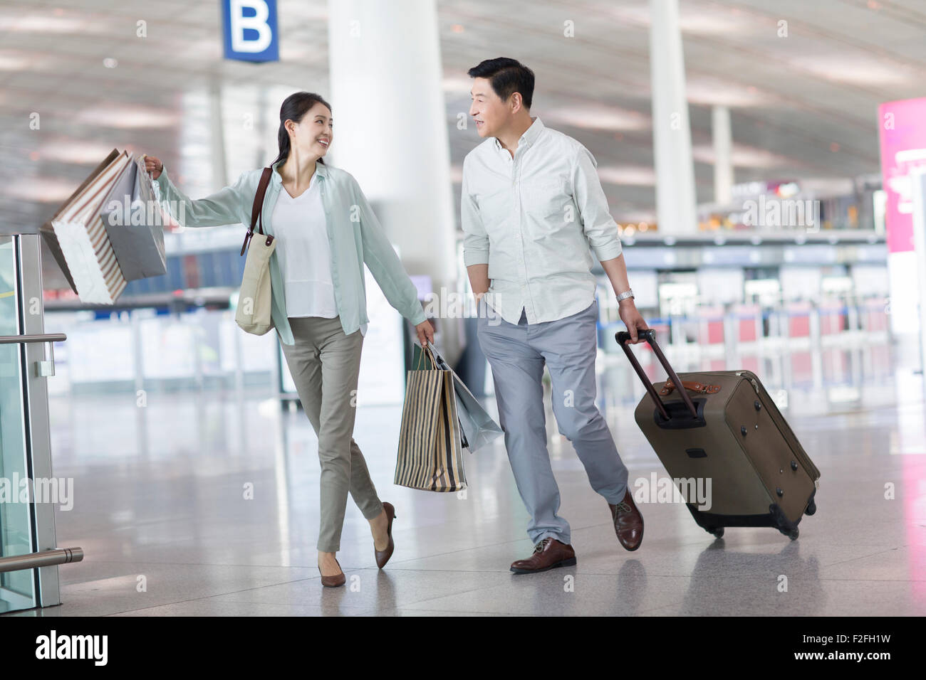 Älteres Paar zu Fuß in Flughafen mit Einkaufstüten Stockfoto
