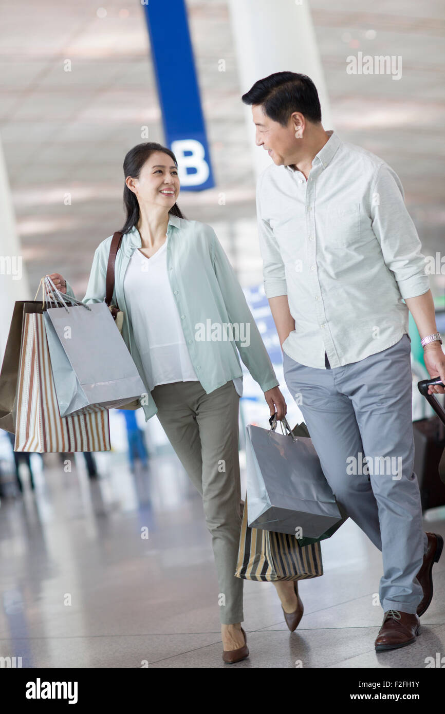 Älteres Paar zu Fuß in Flughafen mit Einkaufstüten Stockfoto