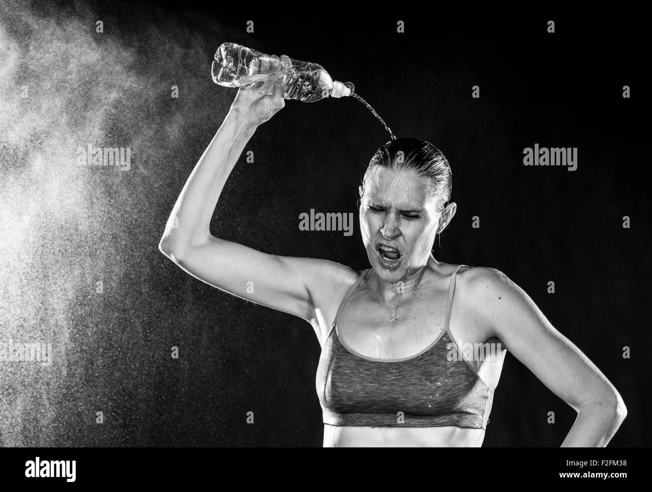 Sportliche Frau gießt Wasser über Kopf müde Stockfoto