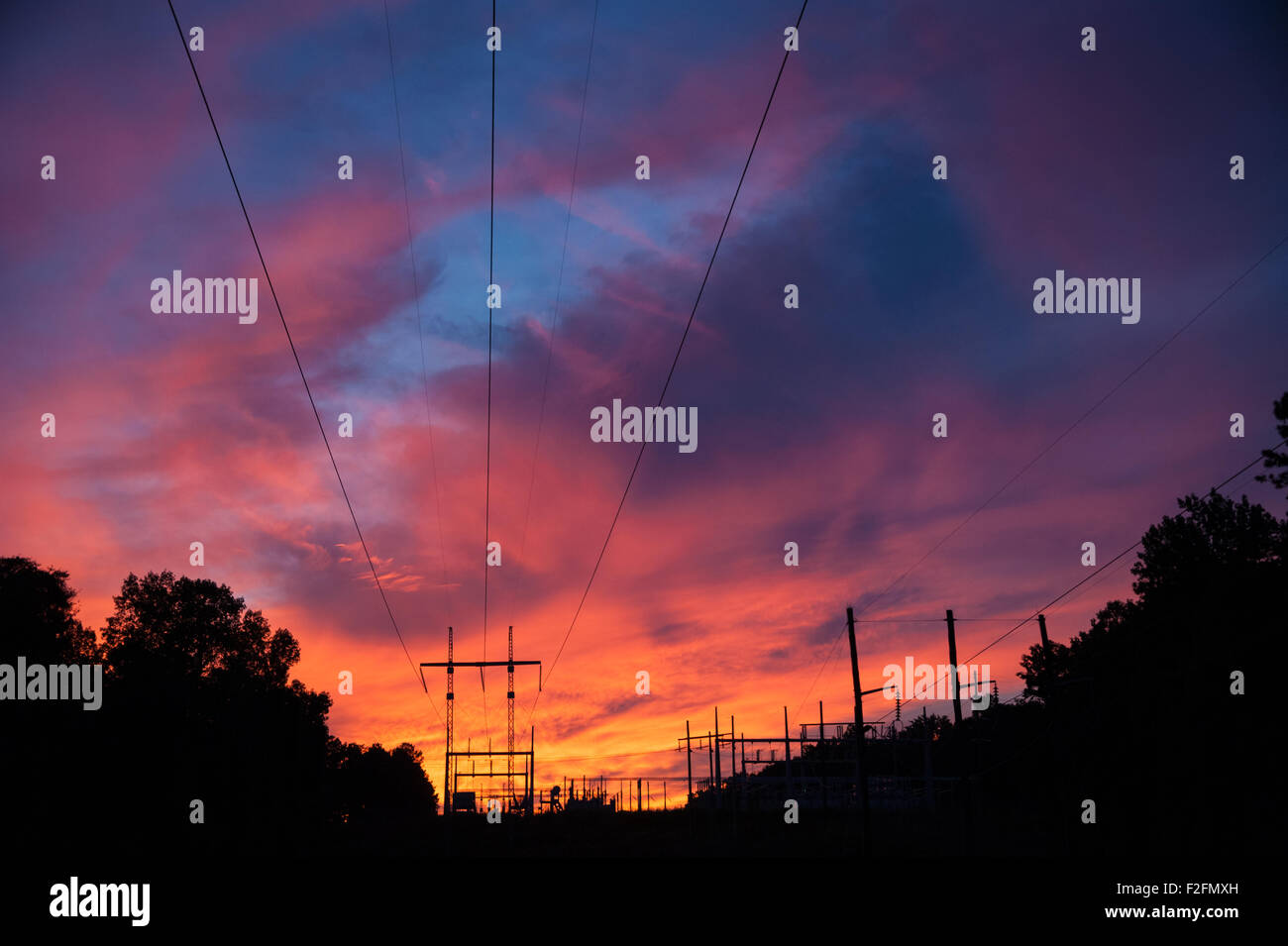 Übertragungsleitungen konvergieren auf eine Umspannstation unter einem lebendigen Sonnenuntergang Himmel in Snellville (Metro Atlanta), Georgia, USA. Stockfoto