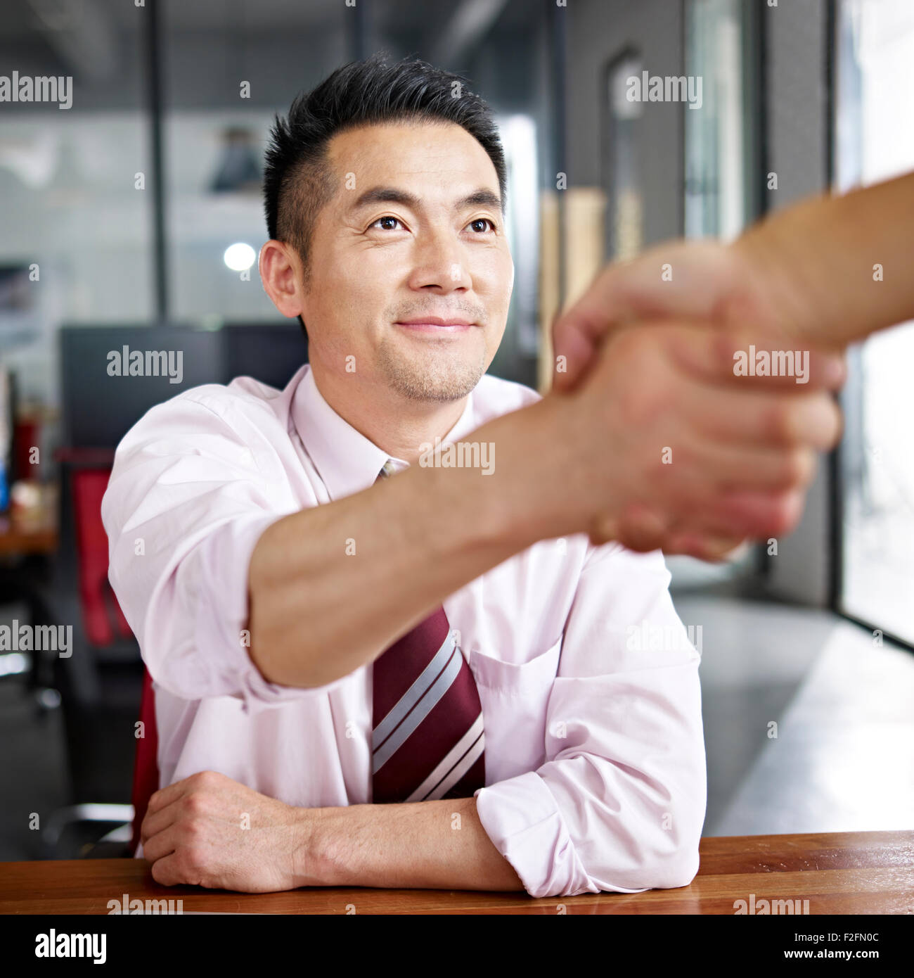 asiatische Geschäftsmann Händeschütteln mit Besucher Stockfoto