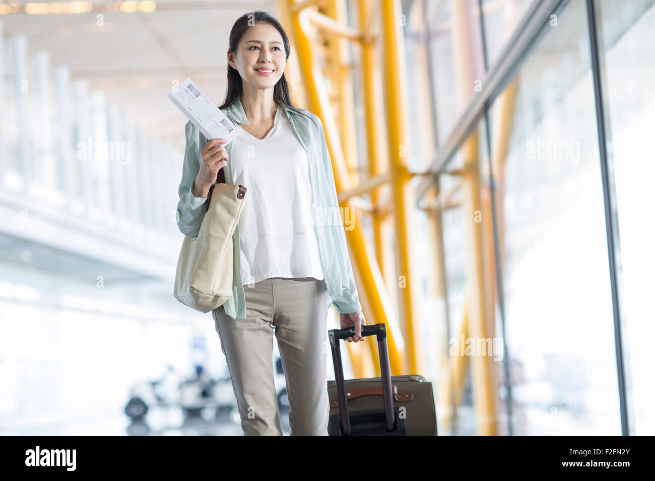 Reife Frau, die zu Fuß in Flughafen mit Koffer Stockfoto