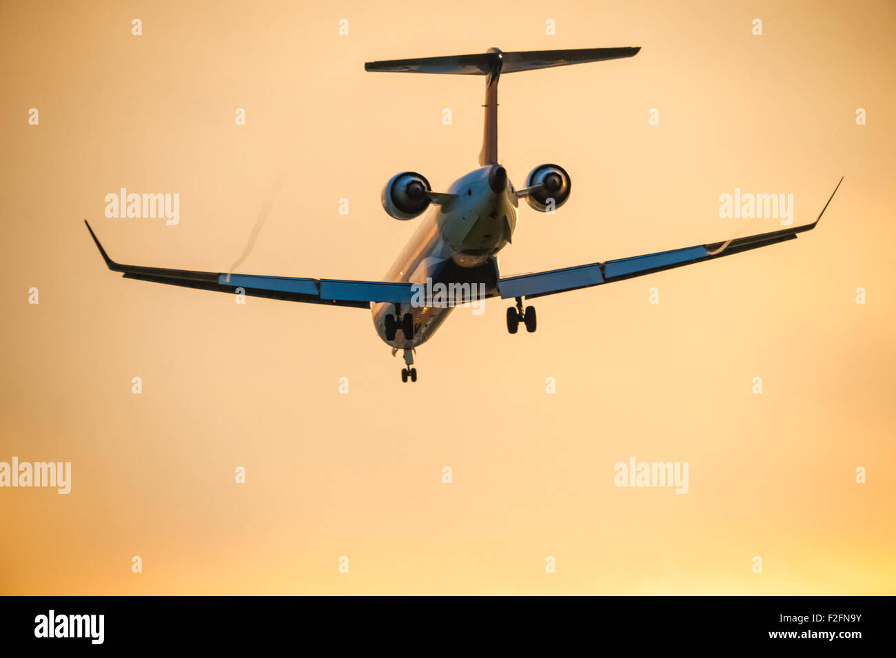 Airline-Passagier-Jet steigt für die Landung unter orange sunset Himmel. Stockfoto