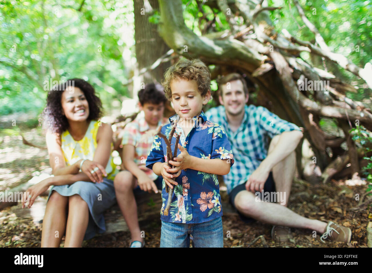 Familie beobachten Jungen spielen mit Stöcken im Wald Stockfoto