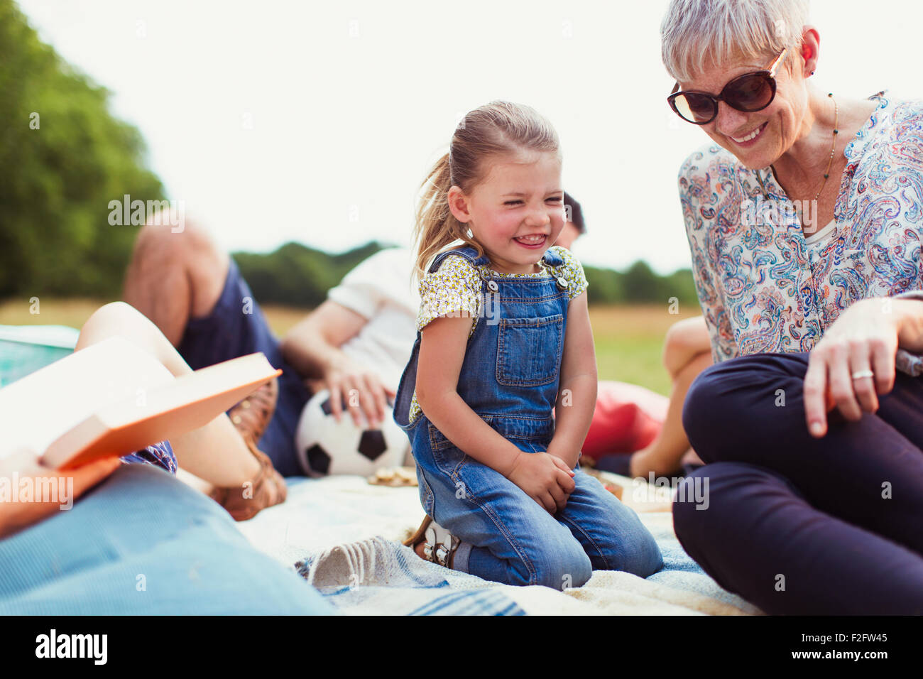Großmutter und Enkelin lachend auf Decke Stockfoto