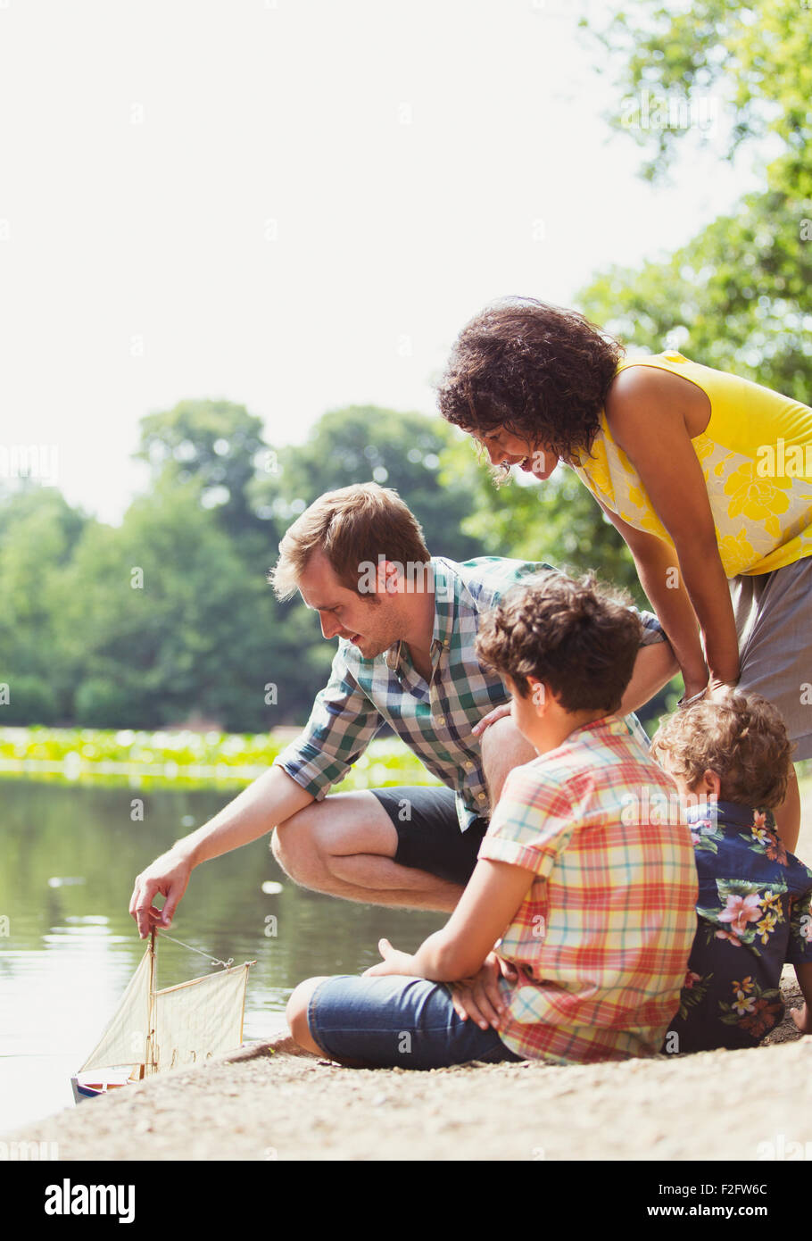 Familie spielt mit Spielzeug Segelboot am See Stockfoto