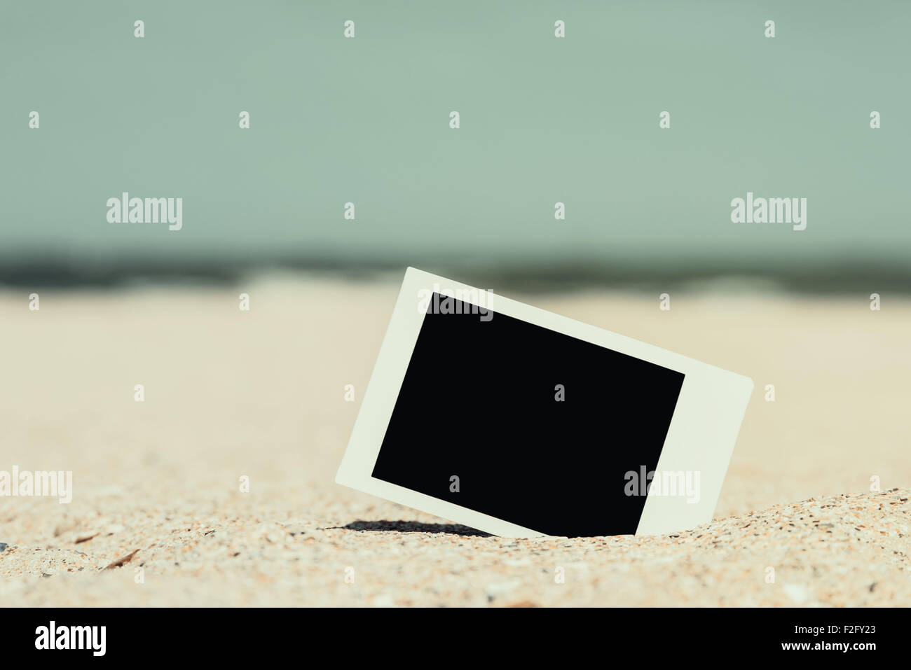 Retro-Foto von leeren Sofortbild-Karte am Strandsand im Sommer Stockfoto