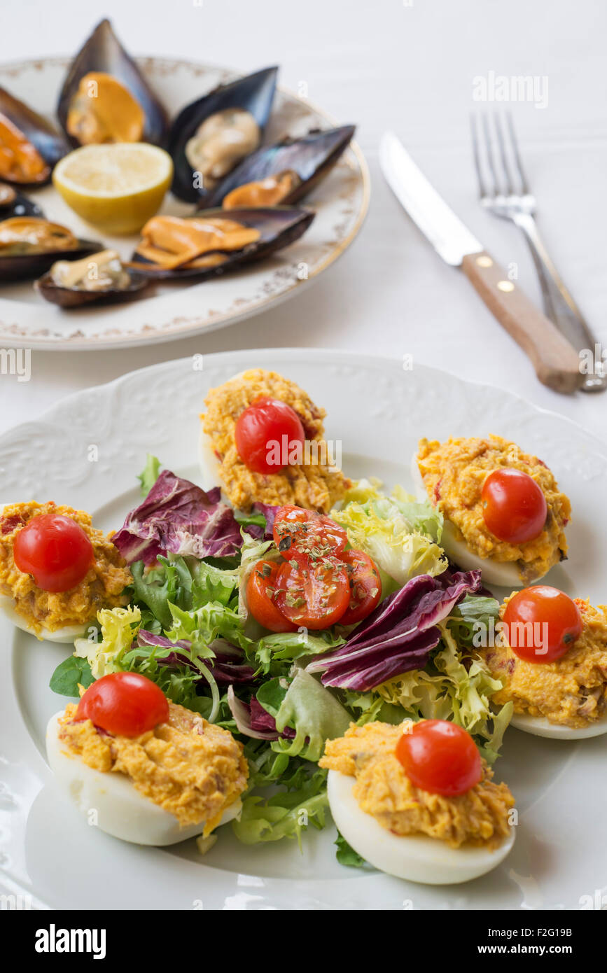 deviled Eiern mit grünem Salat und Kirschtomaten. der Hintergrund ist Muscheln gedämpft. Stockfoto