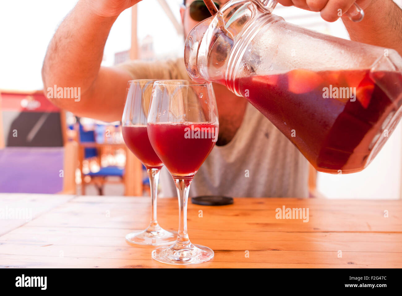 Man gießt Sangria in zwei Weingläser sonnigen Hintergrund Stockfoto