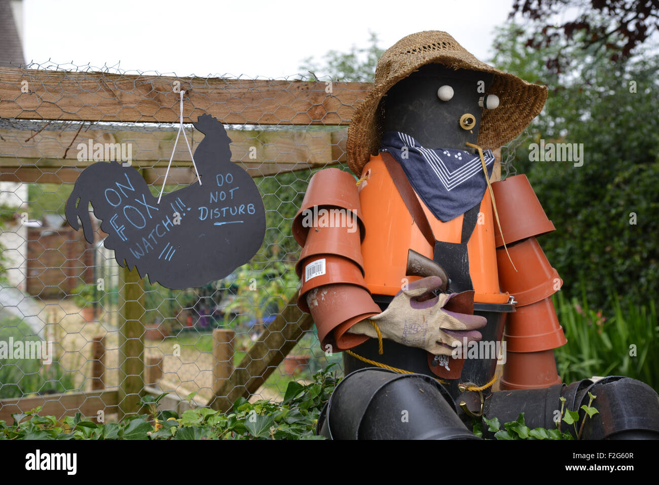 Vogelscheuche aus Blumentöpfen zusammen mit humorvollen Zeichen im Norden Oxfordshire Dorf Hook Norton gemacht Stockfoto
