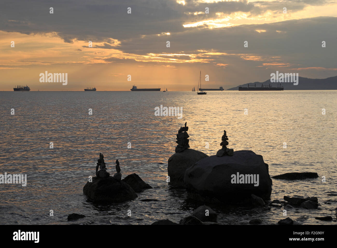 Sonnenuntergang vom Sonnenuntergang Strand English Bay Vancouver zeigen Schiffe am Anker und Nachahmung Inukshuk Stockfoto