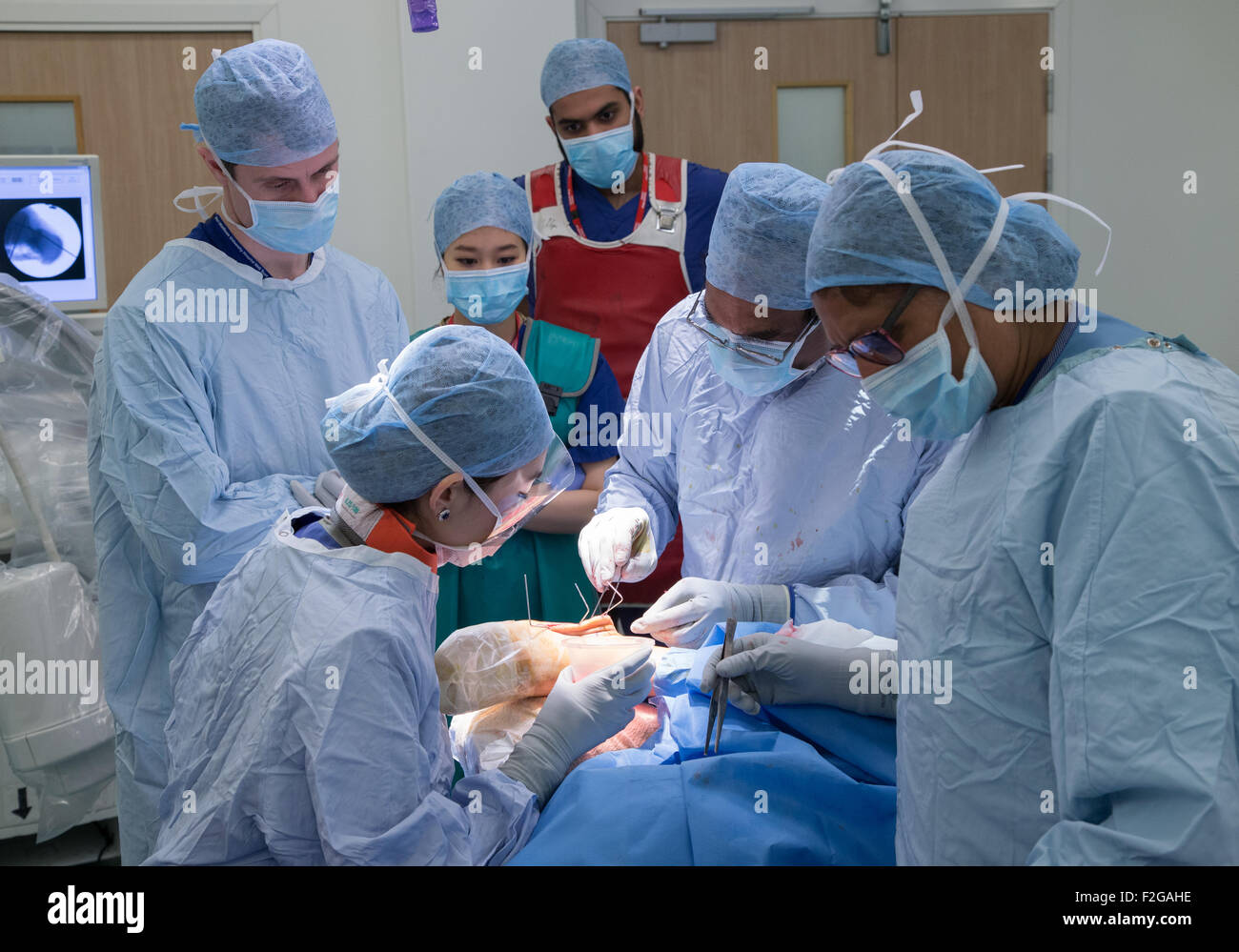 Chirurg und medizinischem Personal im Operationssaal in einem NHS Krankenhaus arbeiten Stockfoto