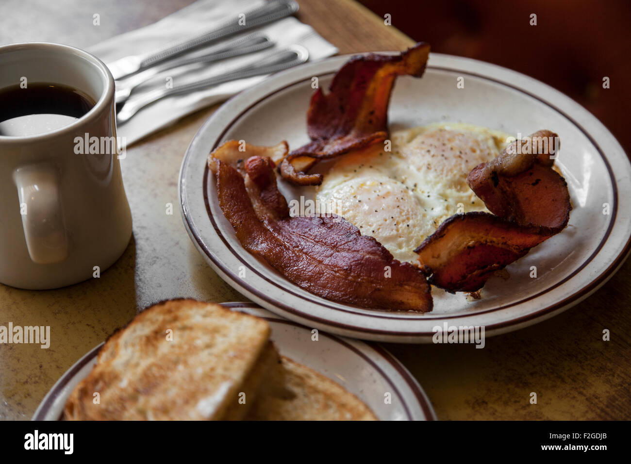 Eiern, Speck, Toast und Kaffee in einem Diner mit Besteck Stockfoto