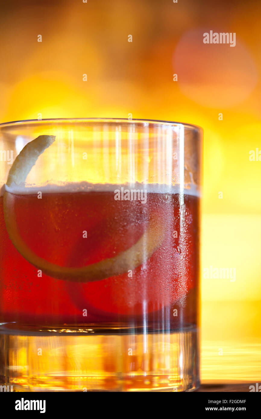 Sazerac mit einer Zitrone twist kurz Glas hinterleuchtet mit gelbem Hintergrund Stockfoto