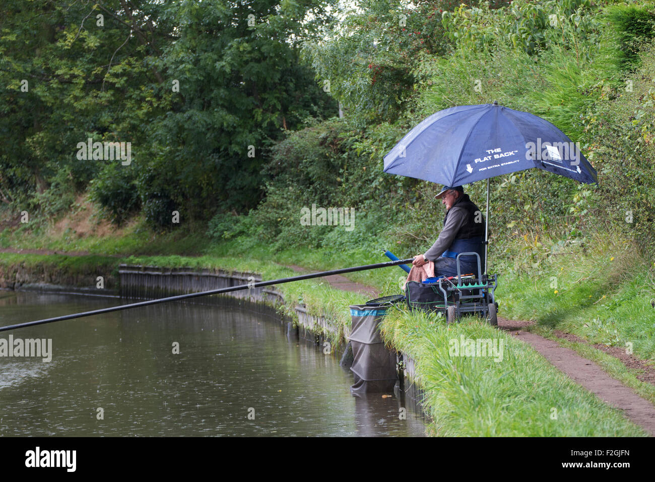 Mann pol Angeln der Regen in der Nähe von Penkridge auf der Staffordshire und Worcestershire Canal, Stockfoto
