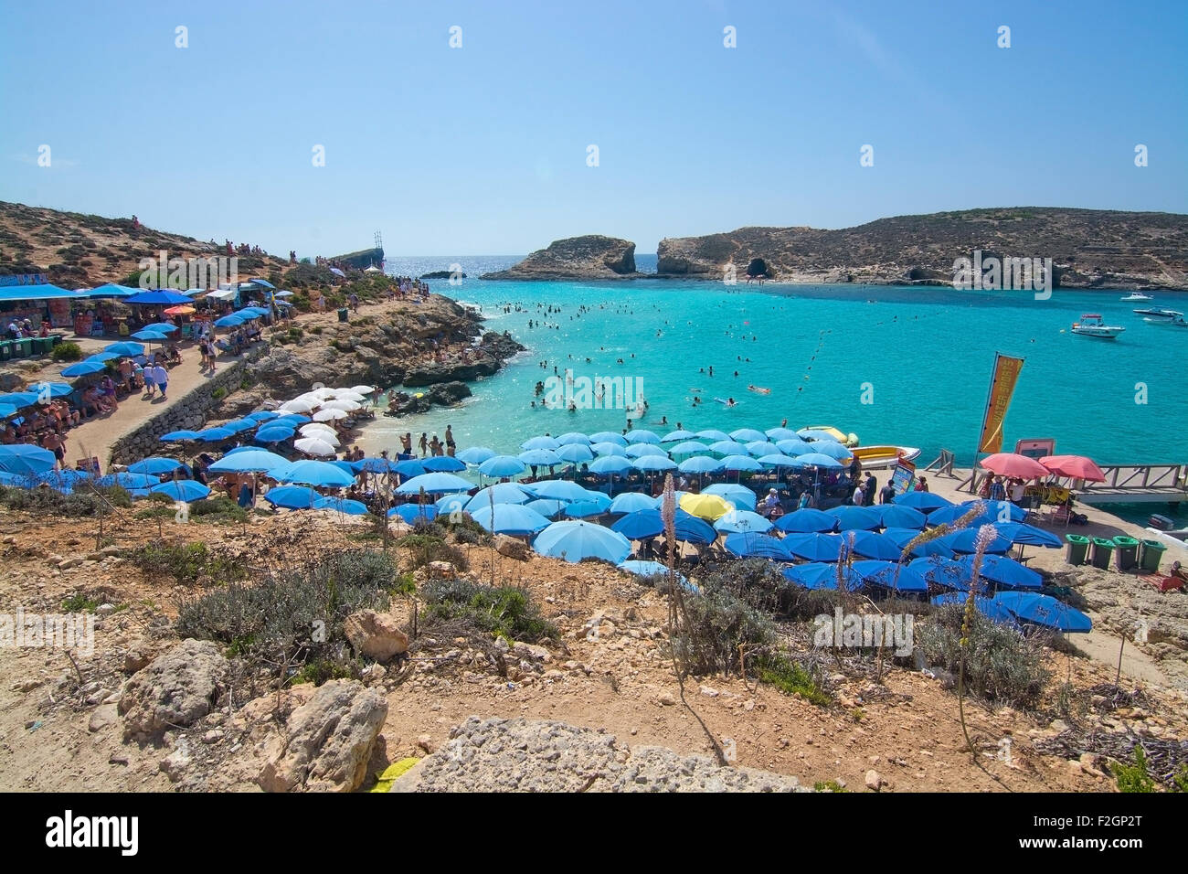 Besucher-Publikum, das klare türkisfarbene Wasser in der blauen Lagune unter Sonnenschirmen an einem sonnigen Tag im September zu genießen. Stockfoto