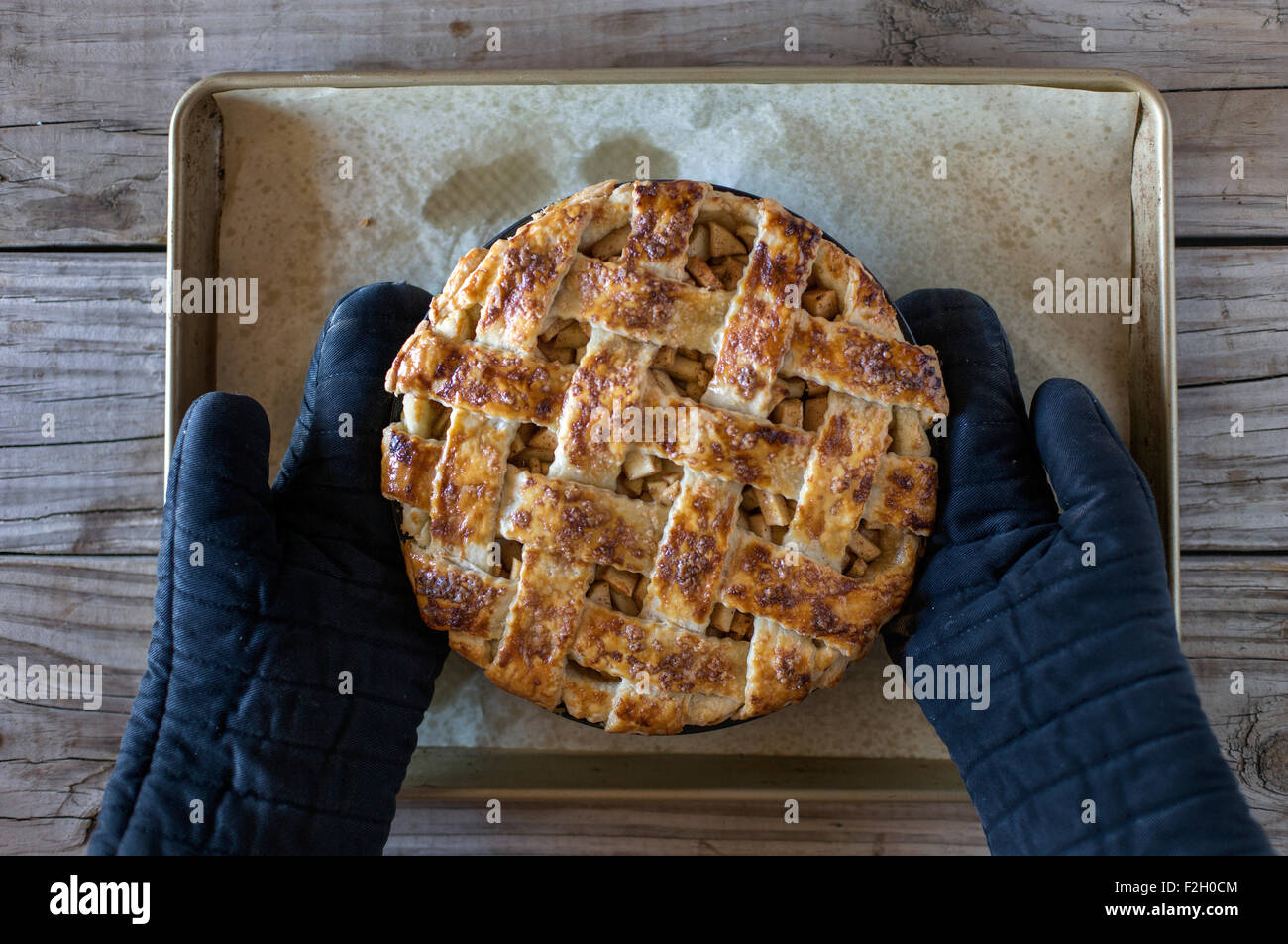 Ein frisch gebackener (noch warmer) Karamell Apfelkuchen ist von einer Person tragen Topflappen auf den Tisch gelegt. Stockfoto