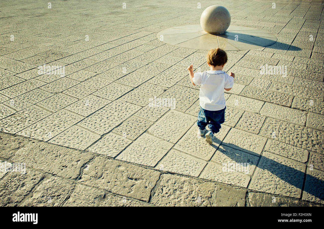 Jungen Baby läuft in Richtung steinerne Kugel, Textfreiraum Stockfoto