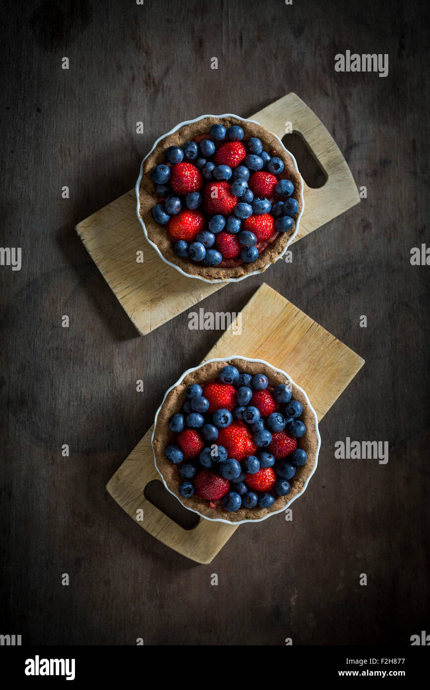 Berry Tartetelets in Backformen auf Holzplatten. Ansicht von oben Stockfoto