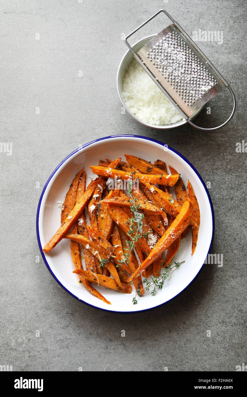 Süßkartoffel-Pommes-frites in eine Emaille-Platte mit geriebenem Parmesan, Gewürze und Thymian Stockfoto