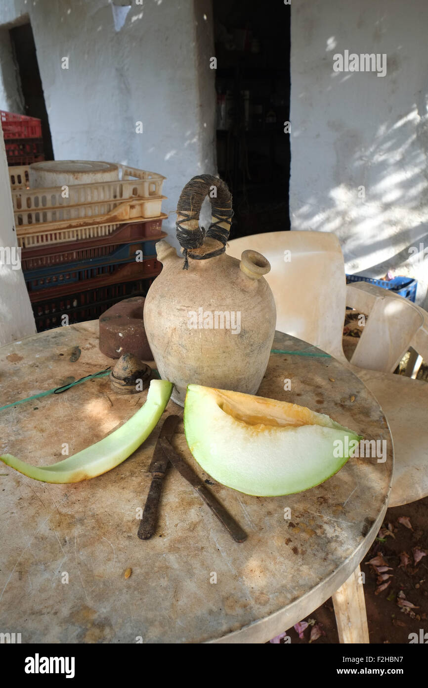 Stillleben von Wasserkrug und Scheibe spanische Melone auf dem Tisch vor Gärtnerschuppen, Menorca, Spanien Stockfoto