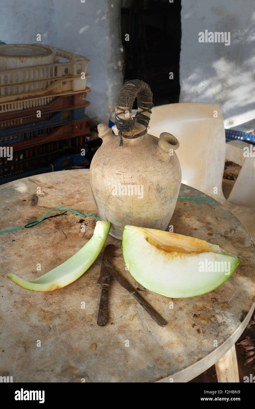 Stillleben von Wasserkrug und Scheibe spanische Melone auf dem Tisch vor Gärtnerschuppen, Menorca, Spanien Stockfoto