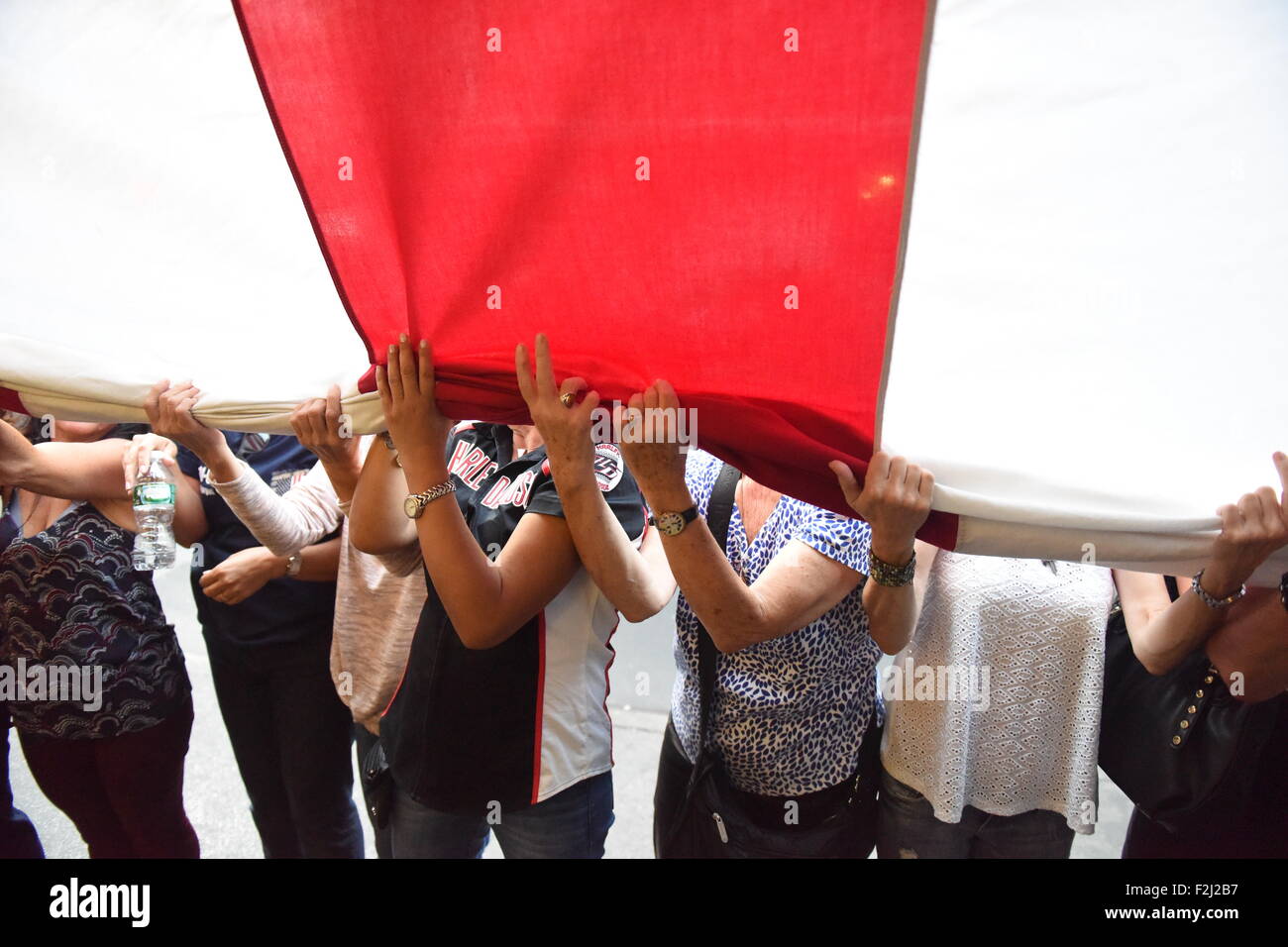 New York City, USA. 19. Sep, 2015. Freiwilligen Frauen halten die Fahne da es hinunter. Absetzung und Faltung des Ground Zero-Flag ist eine jährliche Zeremonie an der Mott Street an der Ecke von Hester geworden. Bildnachweis: Andy Katz/Pacific Press/Alamy Live-Nachrichten Stockfoto