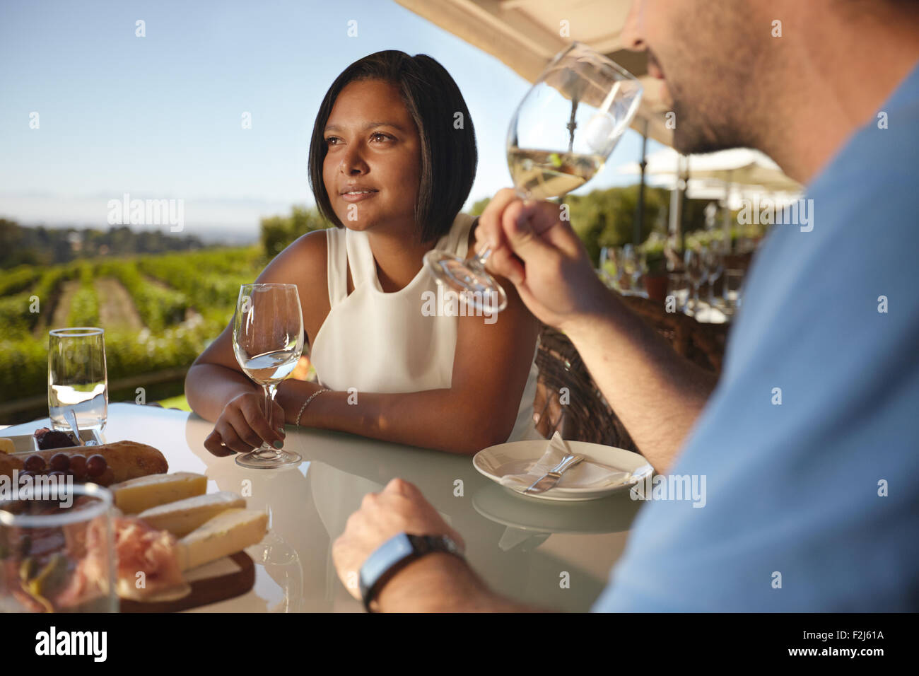 Junge Frau mit einem Mann, Wein zu trinken. Paar im Urlaub in Outdoor-Wein-Bar-Restaurant von einem Weinberg. Stockfoto