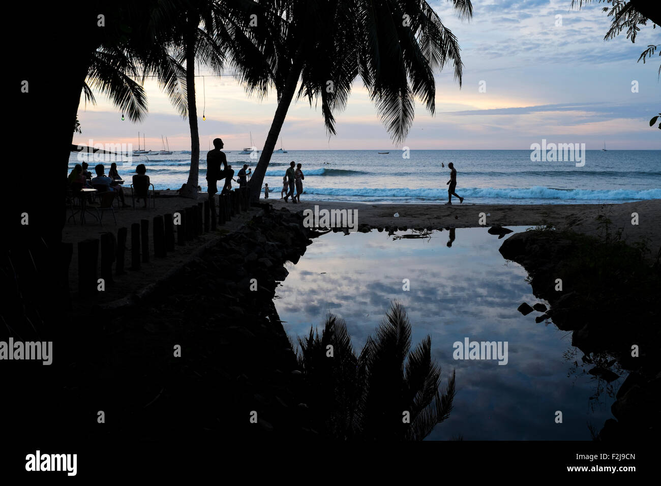 Gruppen von Menschen spazieren am Strand in Playa Tamarindo Guanacaste, Costa Rica in der Dämmerung und Sonnenuntergang. Stockfoto