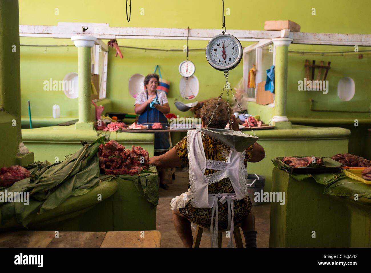 Frauen sprechen und beobachten Sie die Fleisch-Stände im Bereich Fleisch auf dem Markt in Granada, Nicaragua. Sonnenlicht-Streams in Stockfoto