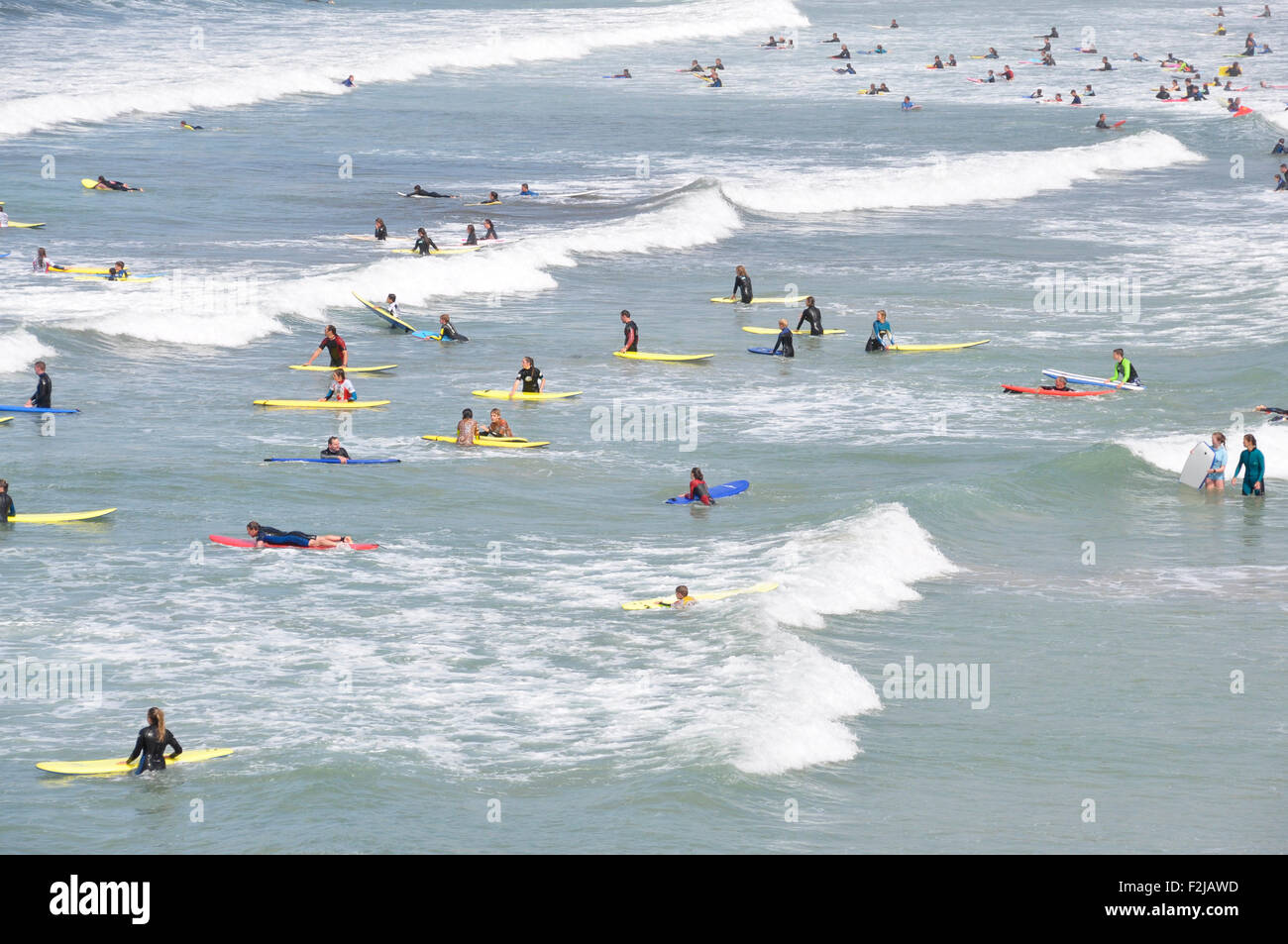 North Cornwall - Polzeath - Surfer Strand - weiße gekrönt Wellenschlag - Surf voller bunter Reiter - jeden Alters - Sonnenlicht Stockfoto
