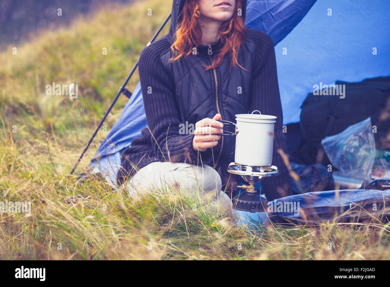 Junge Frau im Zelt kochen mit camping Kocher Stockfoto