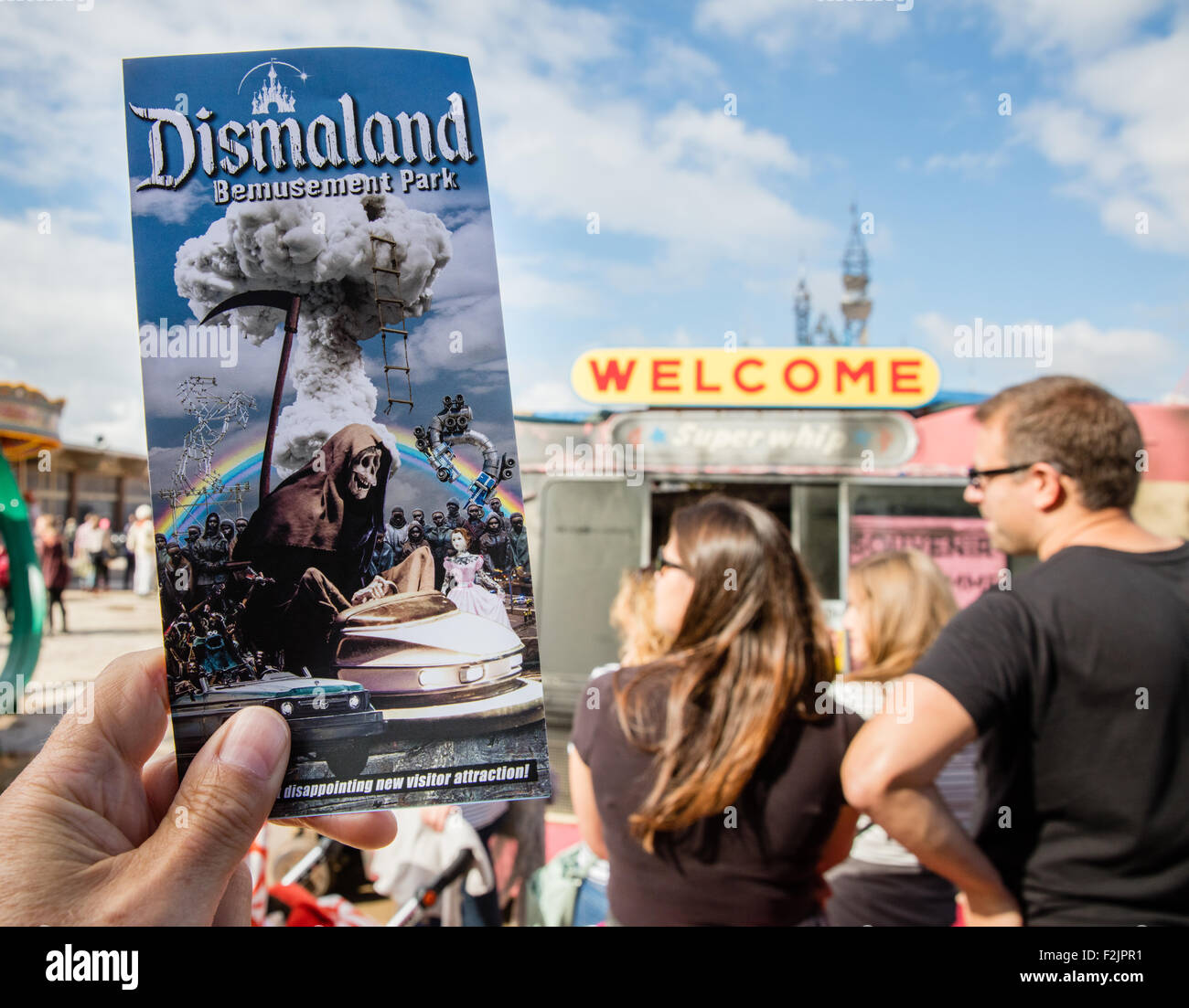 Besucher zum Banksy Dismaland Verblüffung Park in Weston super Mare hält eine Broschüre an den Kunden Dienstleistungen willkommen van Stockfoto