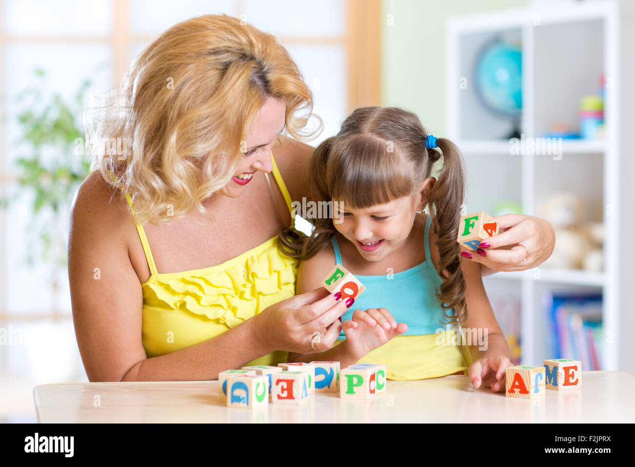 Mutter und ihr Kind spielen mit Würfeln und Buchstaben lernen Stockfoto