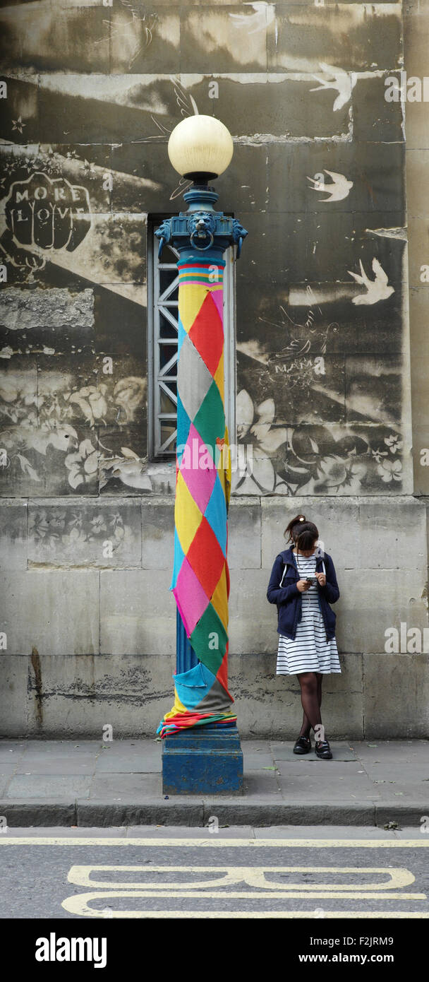 Eine junge Frau und ihr Handy neben einem fröhlich bekleidet Lampe post auf Nelson Street im Stadtzentrum von Bristol UK Stockfoto