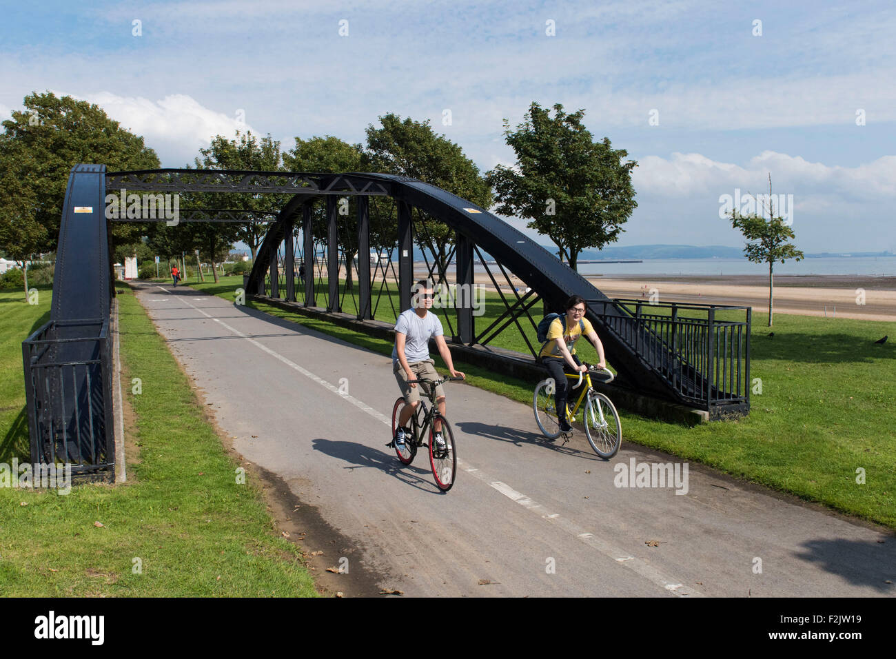 Radfahrer fahren in einen Radweg entlang der Strandpromenade Swansea in Swansea, Südwales. Stockfoto